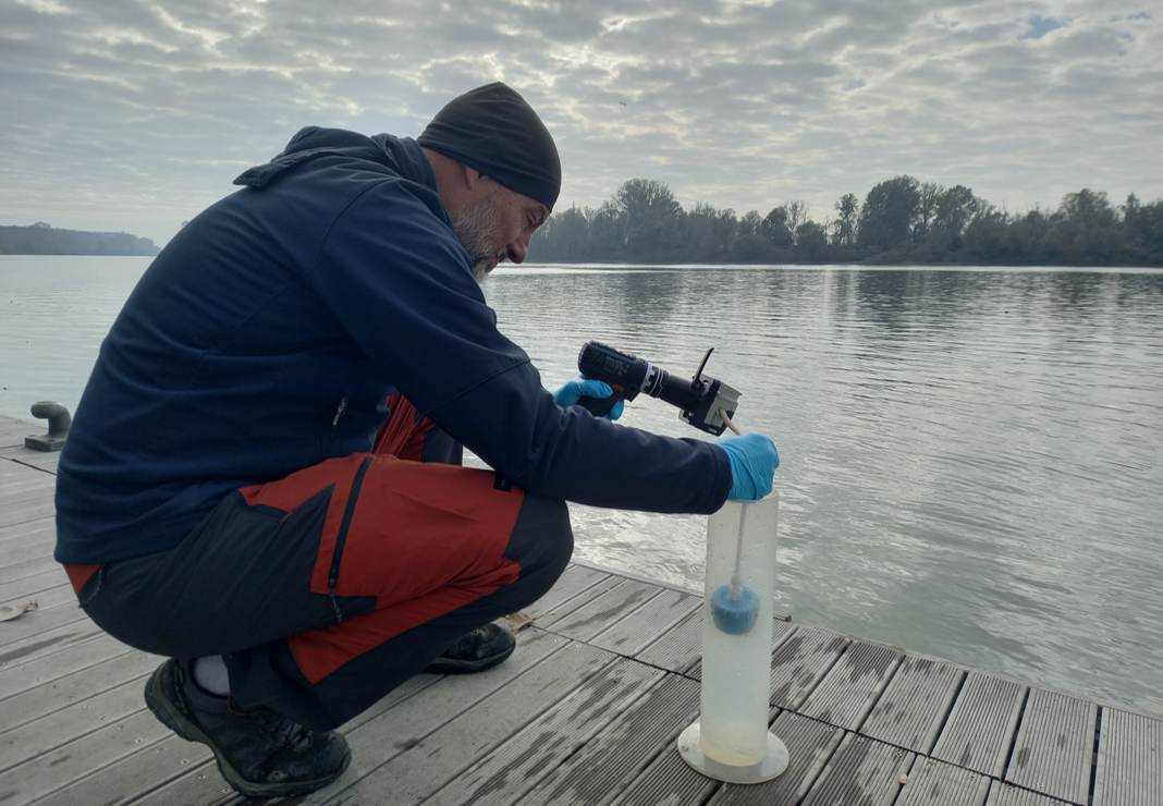 Ricercatore filtra un campione d'acqua del fiume Po su un pontile per l'estrazione del DNA ambientale